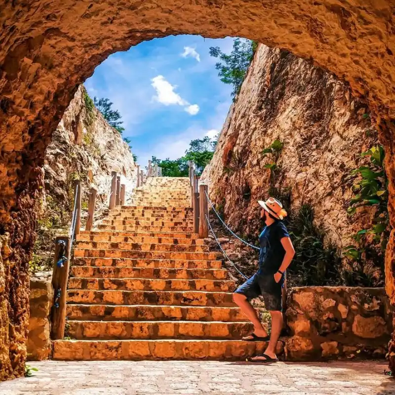 Xooch semi-open cenote entrance with limestone walls and native vegetation at Santa Bárbara